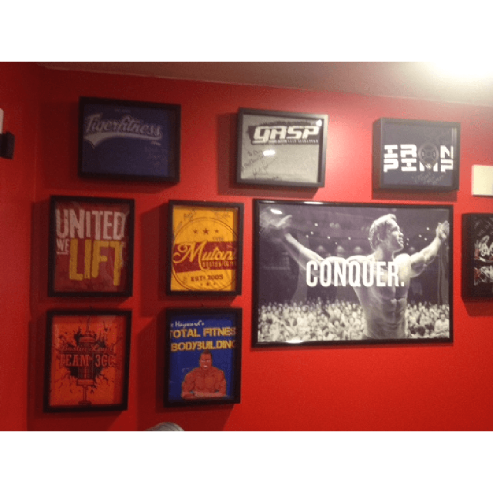 Gym decor with Arnold Schwarzenegger poster and weightlifting t-shirts framed and displayed in Shart Original T-Shirt Frames