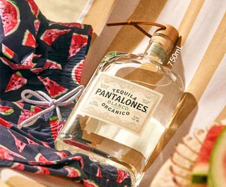 Bottle of Pantalones tequila on a chair with a patterned fabric.