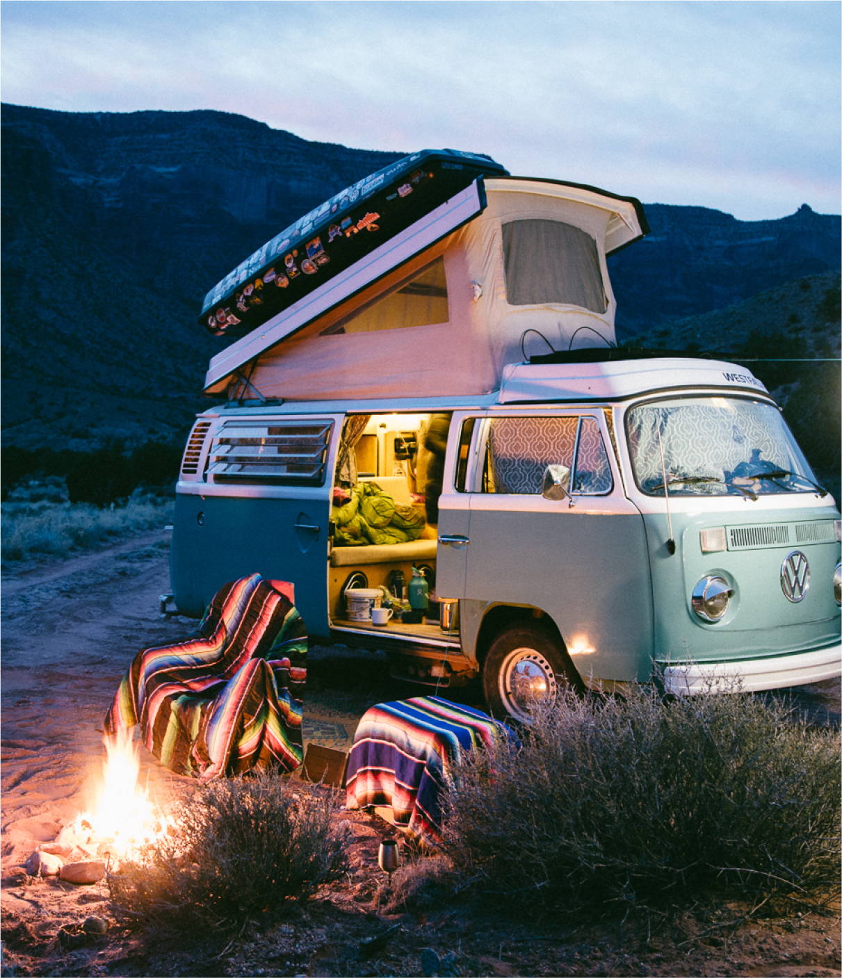 a camper van with a campfire in the foreground
