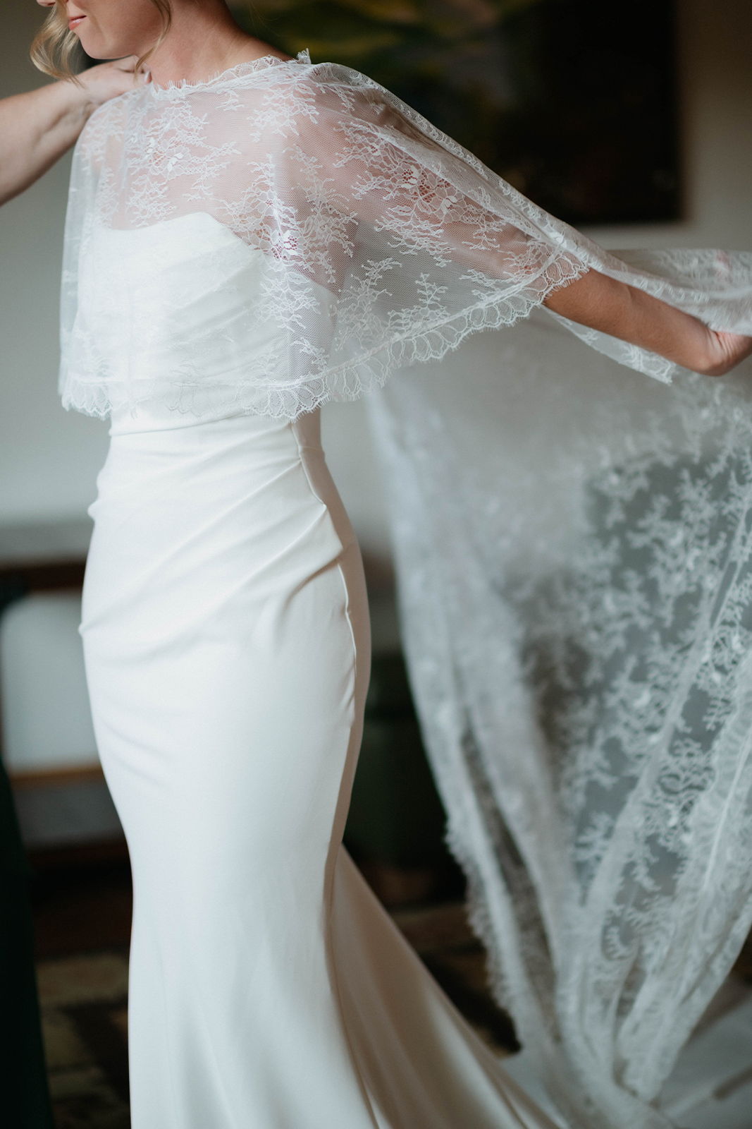 Bride wearing a white dress with a lace cape.