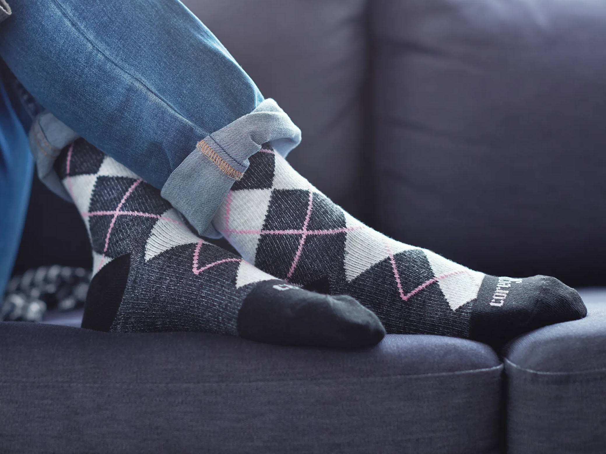 Person lounging on couch while wearing Core-Spun Gradient Compression Socks in Pink Argyle