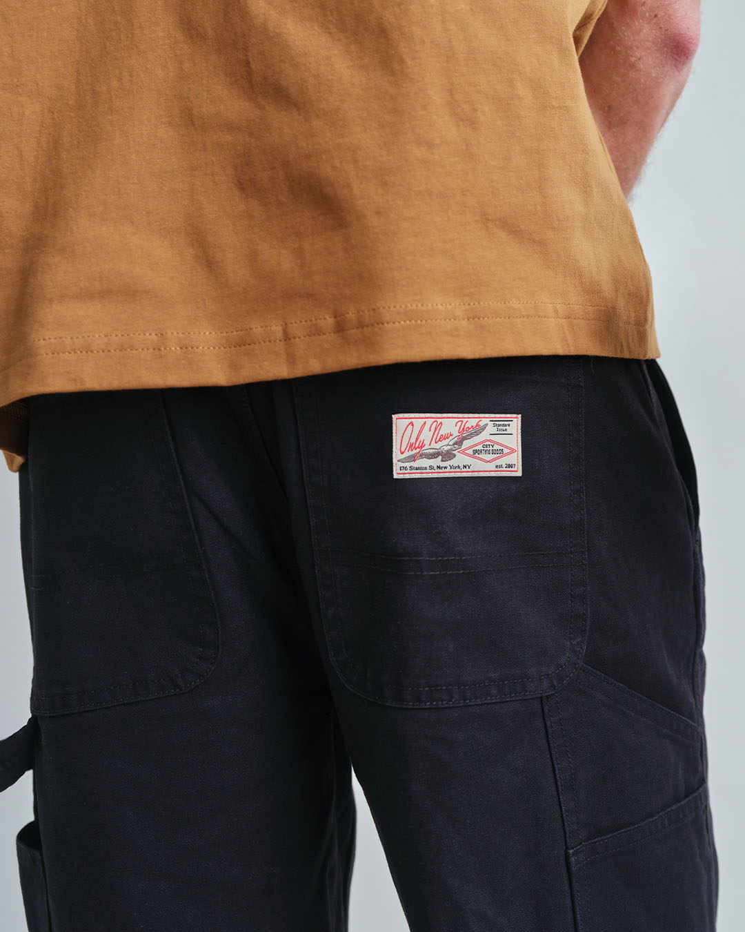 Person wearing a brown shirt and black pants with a label on the back.