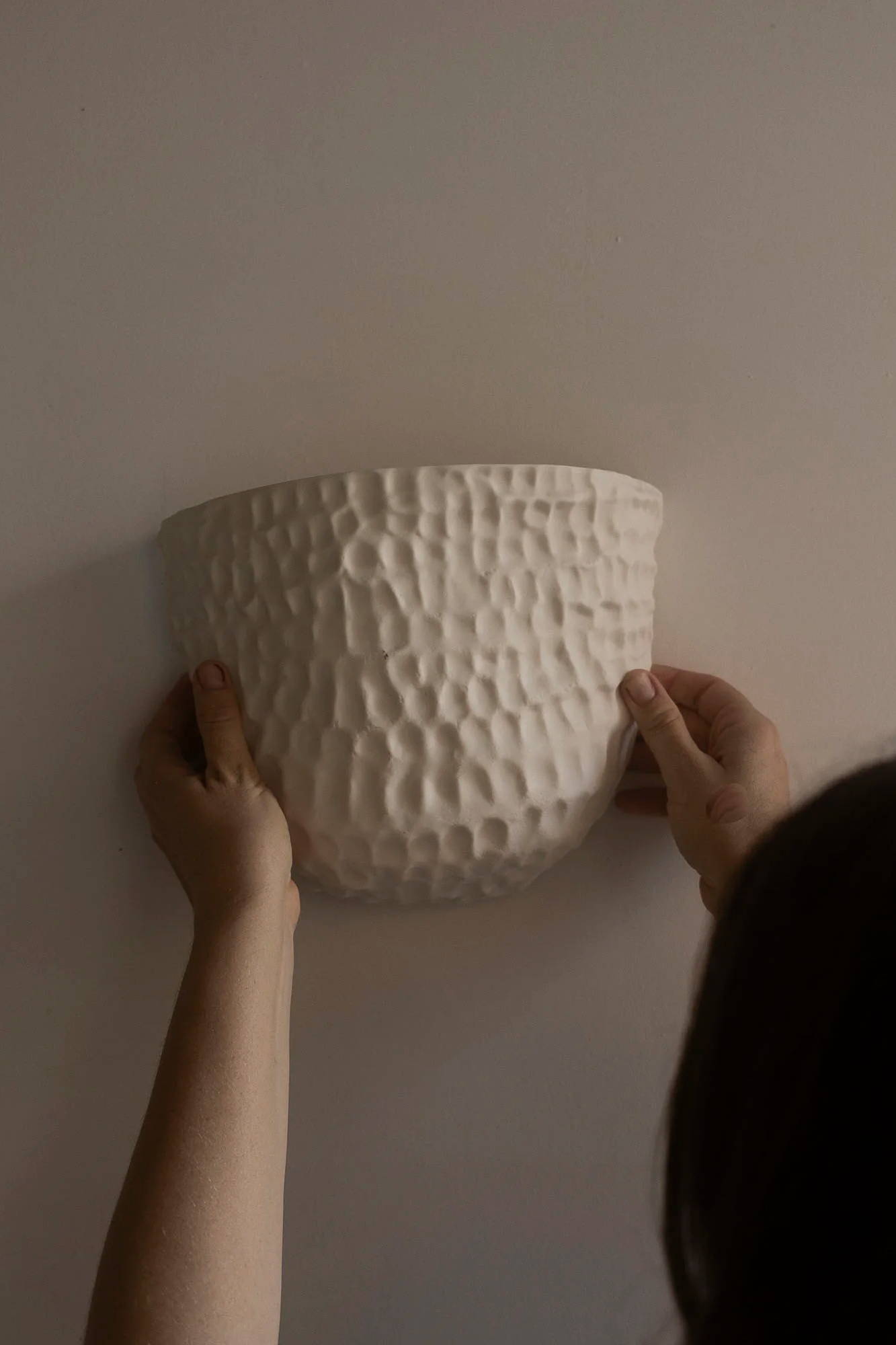 Person installing the Pinched wall sconce from Milly Dent.