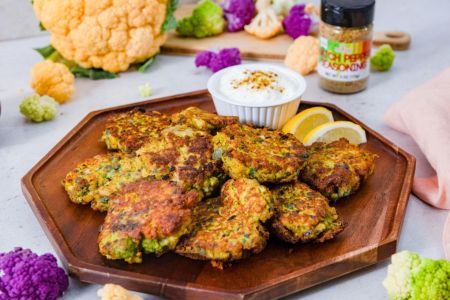 Fried cauliflower patties served with yogurt dip and lemon slices.