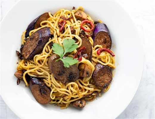 Bowl of noodles with eggplant, chili, and garnished with cilantro.