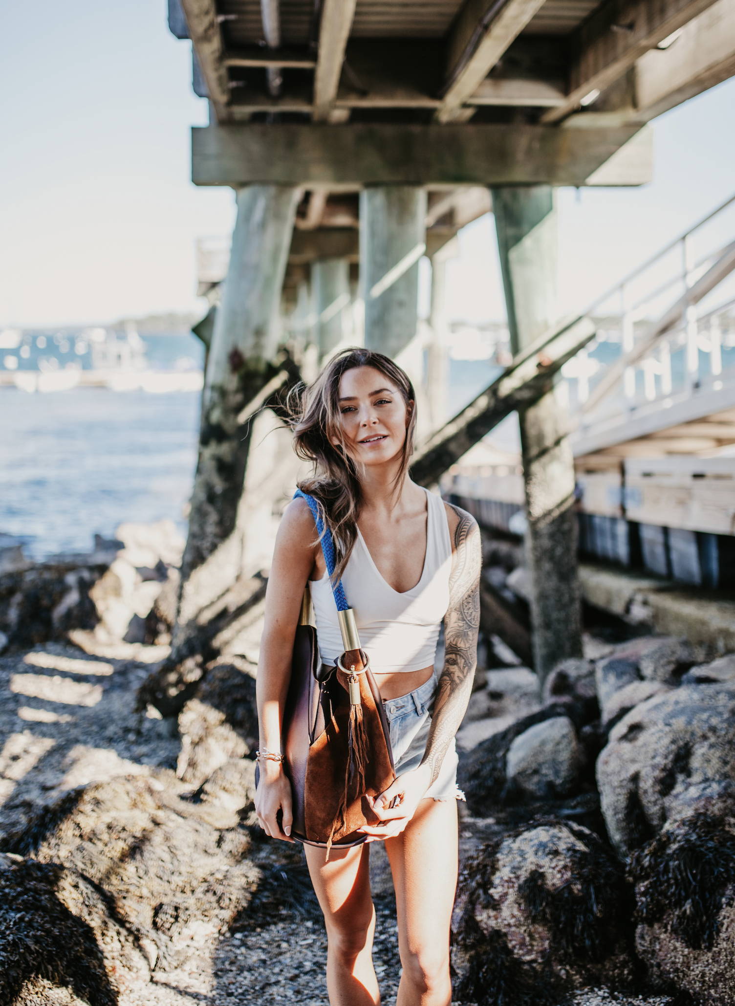 model wearing brown leather tote by a dock with leather seaweed tassel
