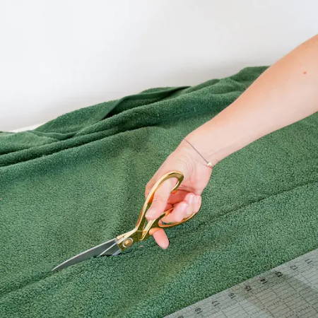 Hand cutting up a beach towel with fabric scissors