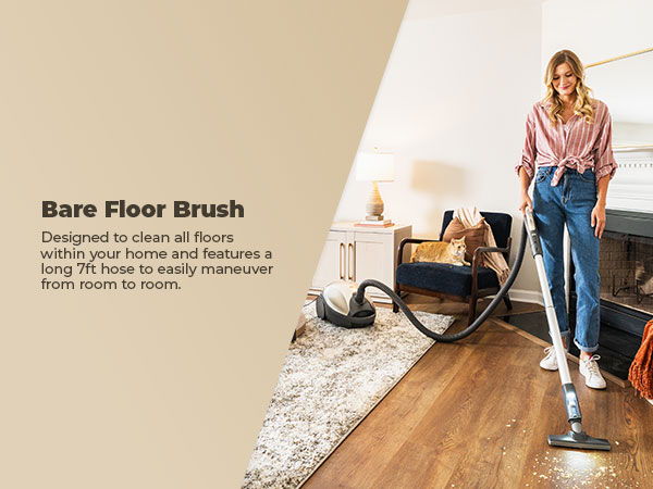 Woman using a vacuum with a bare floor brush in a living room.