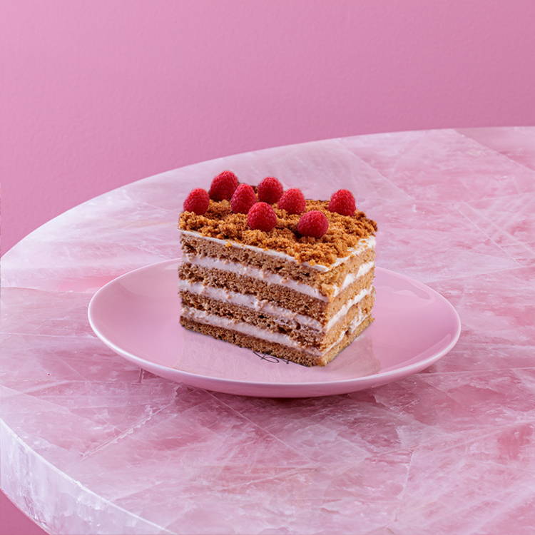 Honey cake with fresh raspberries on pink plate