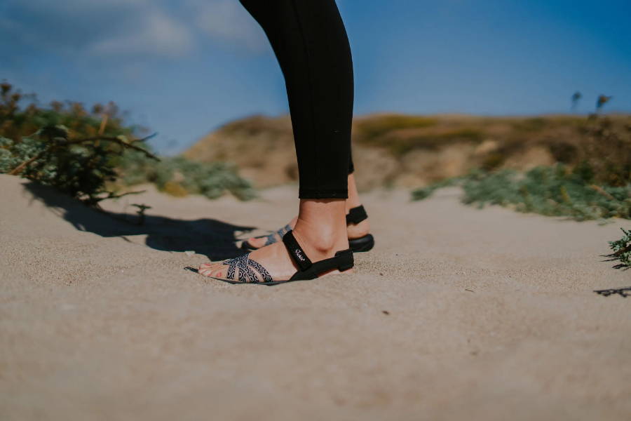 woman standing on beach in vegan sandals