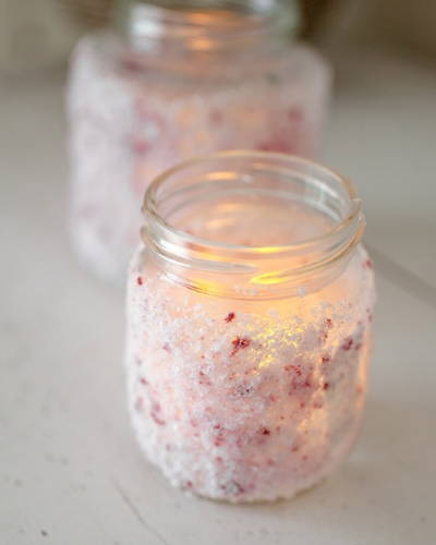 Pink salt mason jar with LED light inside on a wooden table.