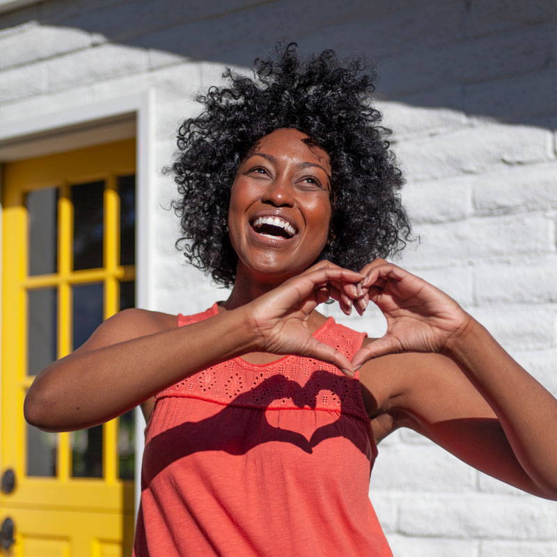 Female model making heart shape with hands.