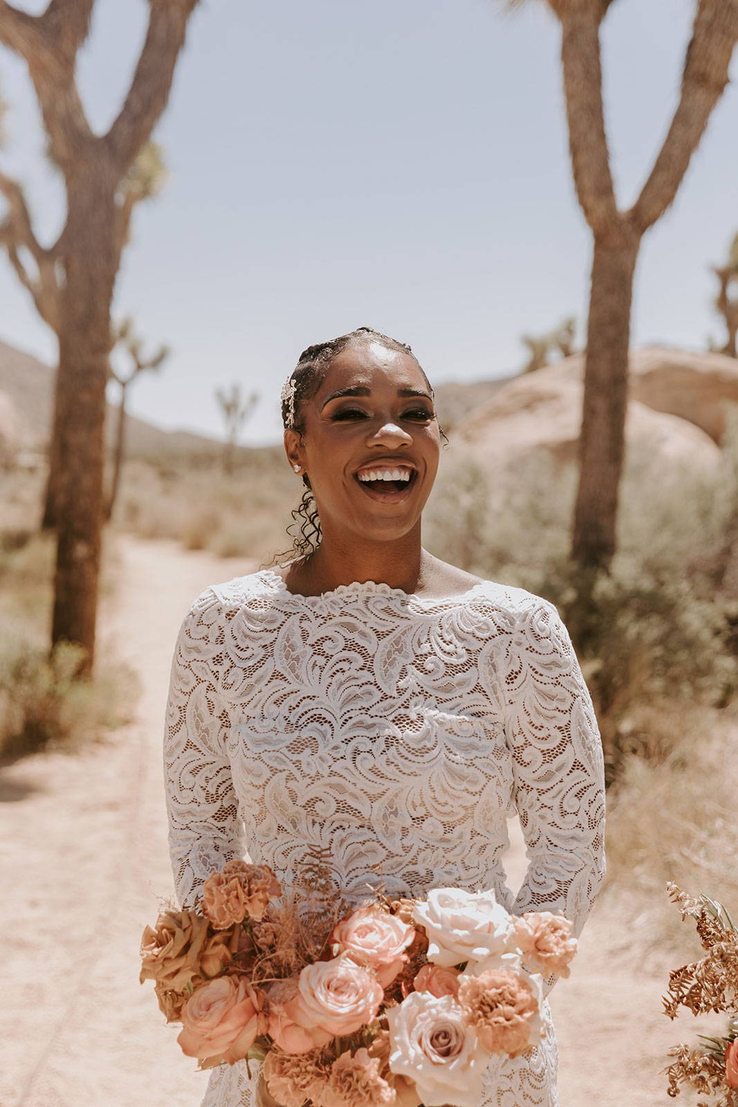 La mariée rit dans sa robe Orla et son bouquet.