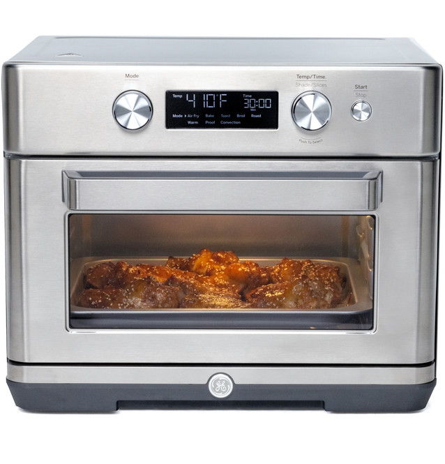 A stainless steel air fryer with visible food inside.