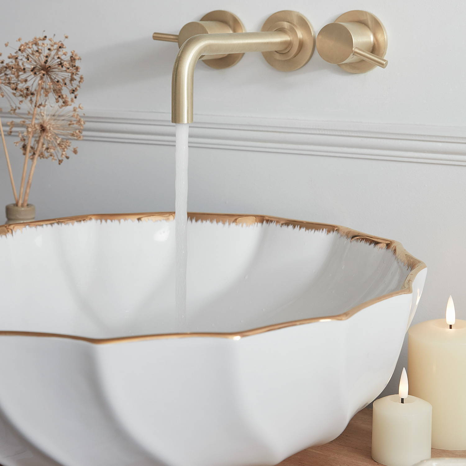 A photos of a white and gold sink with gold taps and LED candles.