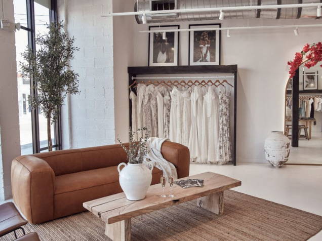 Grace Loves Lace Kleider hängen mit Terrakotta-Couch und erdfarbenem Ausstellungsraum