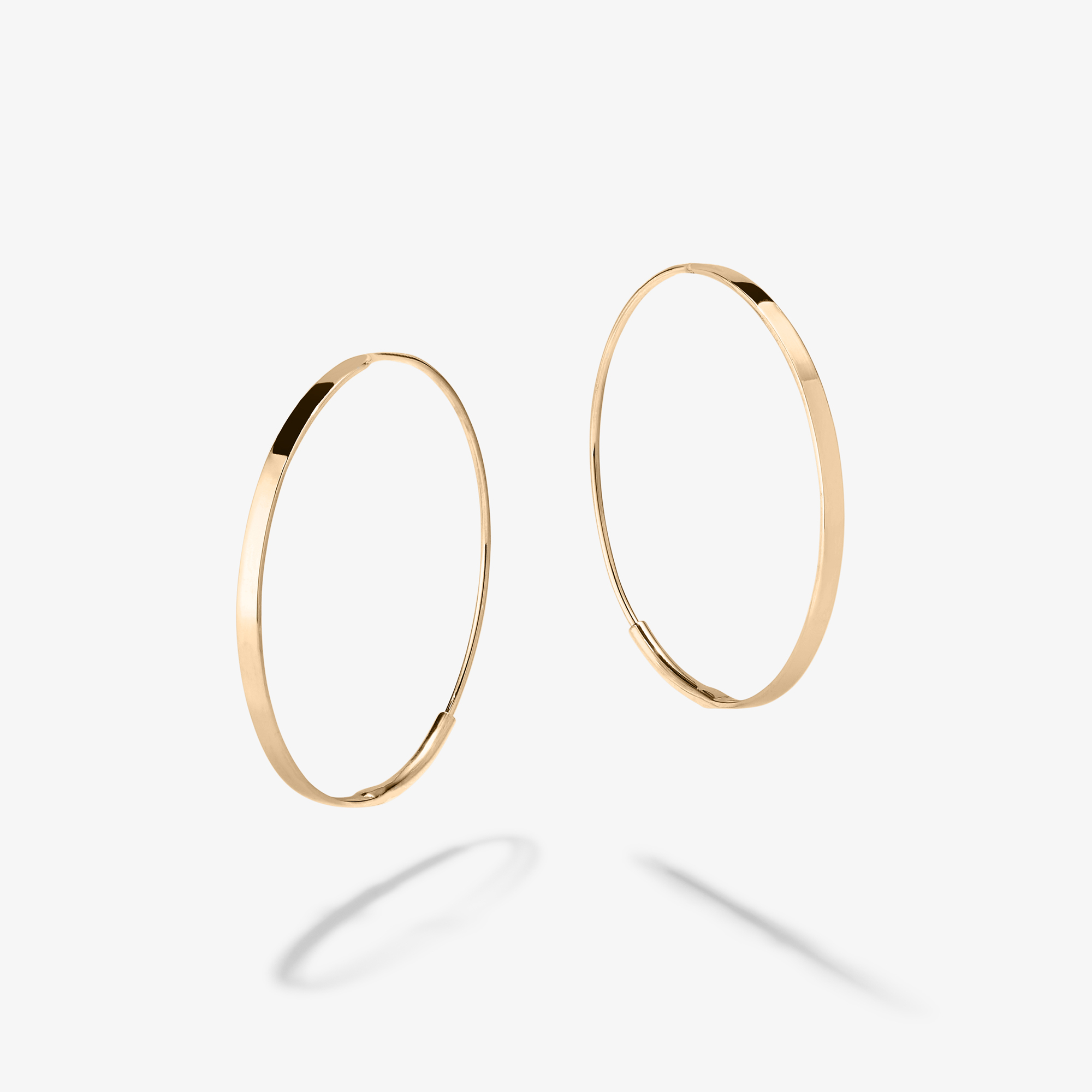 Two gold hoop earrings with a simple design and soft shadows.