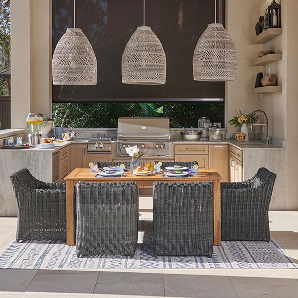 Outdoor dining area with a wooden table, chairs, and hanging light fixtures.