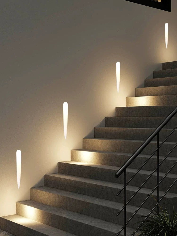Tapered gypsum wall lights set at even intervals along a dark staircase, lighting each tread without glare
