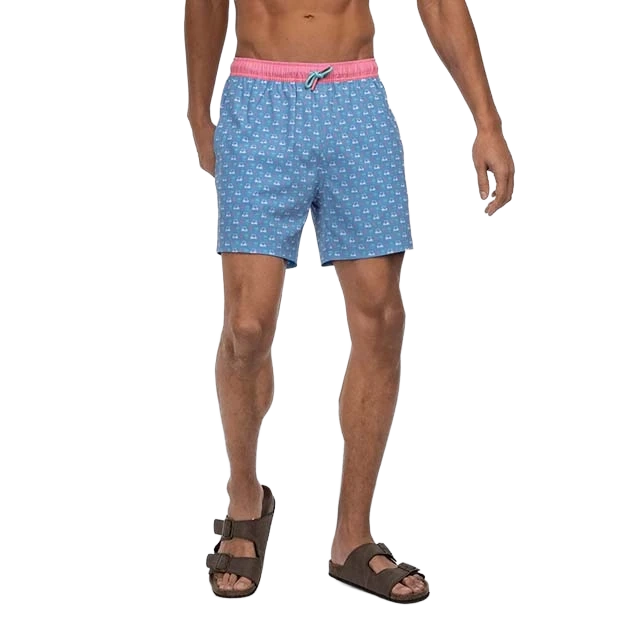 Man wearing blue patterned swim shorts and sandals.