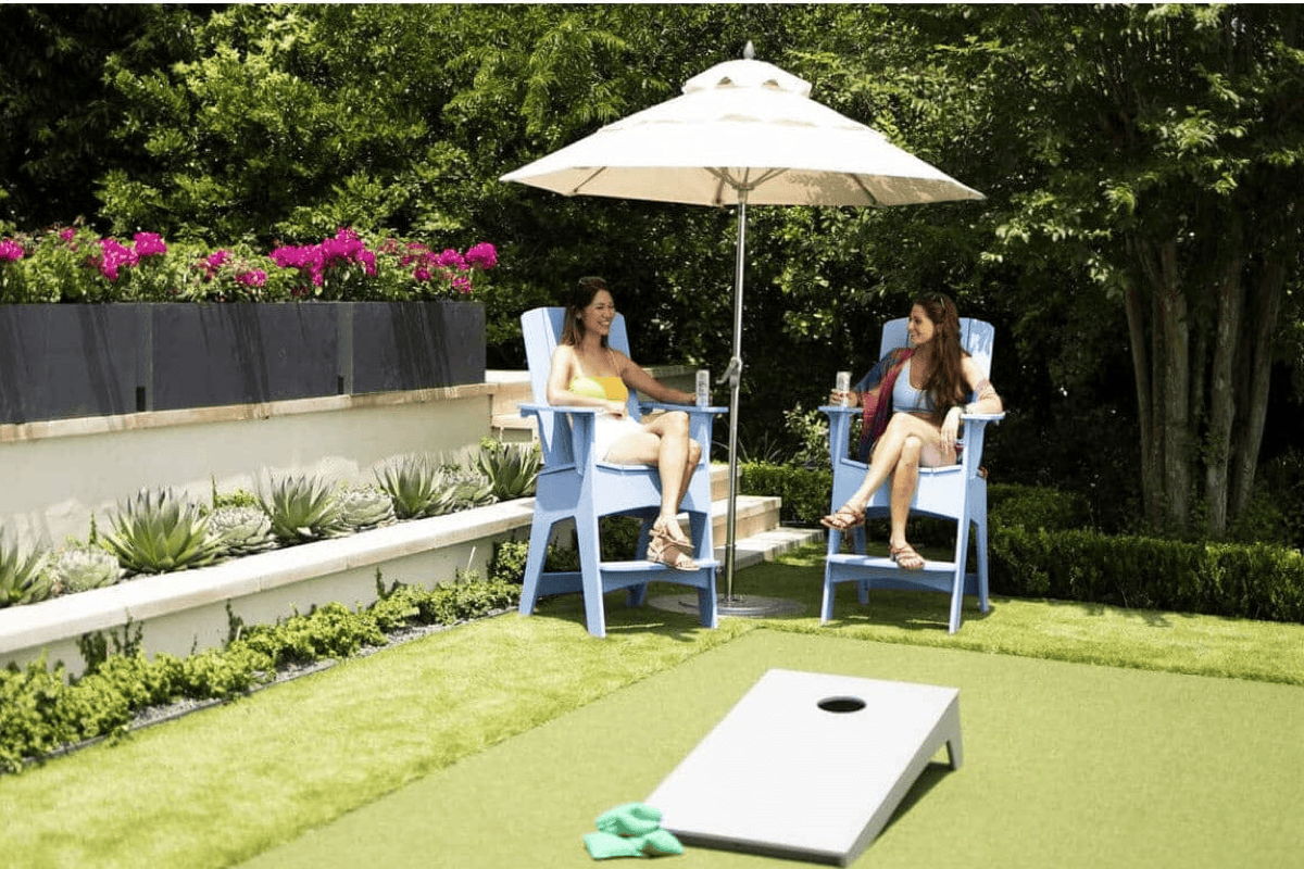 Backyard lounge area with patio umbrella, blue outdoor chairs, and shaded seating for casual outdoor entertaining.