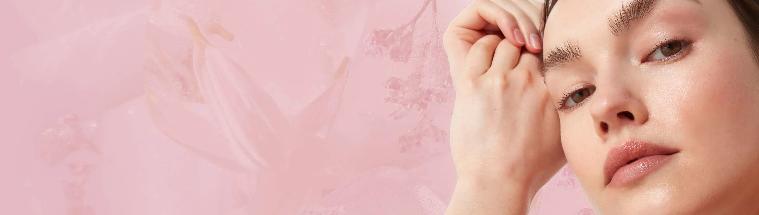 Woman touching her face against a soft pink background.