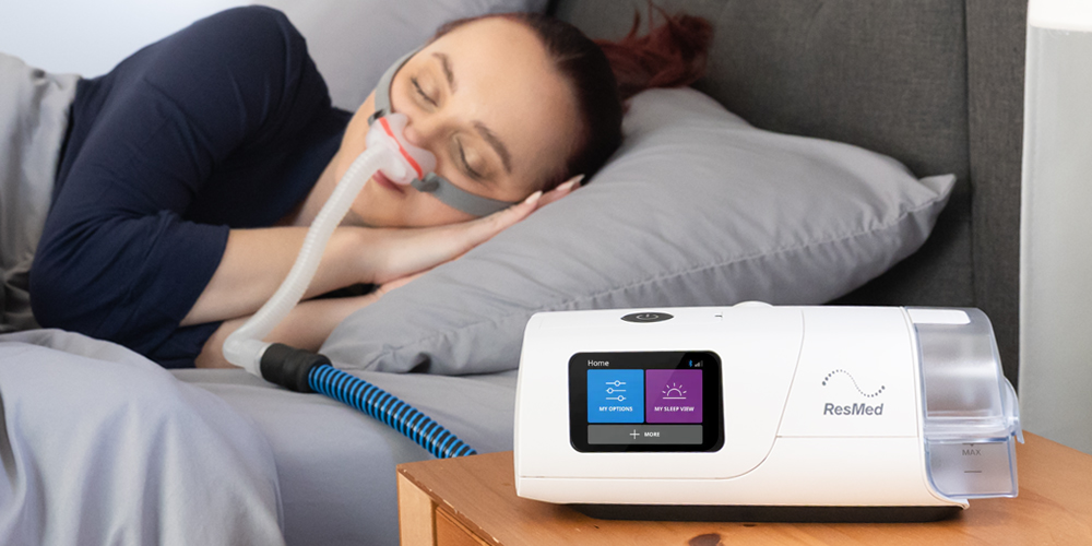 Person sleeping with a CPAP machine beside them on a nightstand.