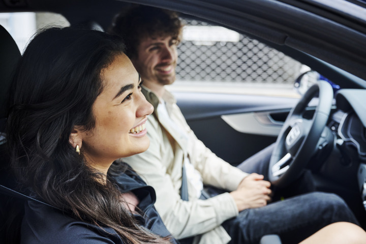 Two smiling people sitting in a car, enjoying a moment together.