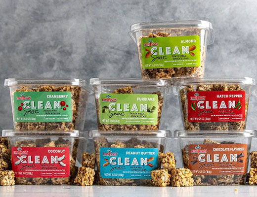 Containers of granola with various flavors stacked on a gray background.