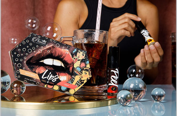 Makeup products with a person holding nail Lip Heal and a drink, surrounded by bubbles.