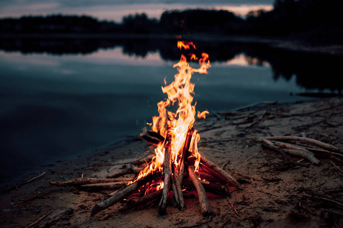 A small fire on rocks overlooking a lake and trees
