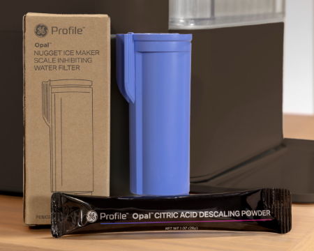 A blue filter holder next to a descaling powder packet and a box.