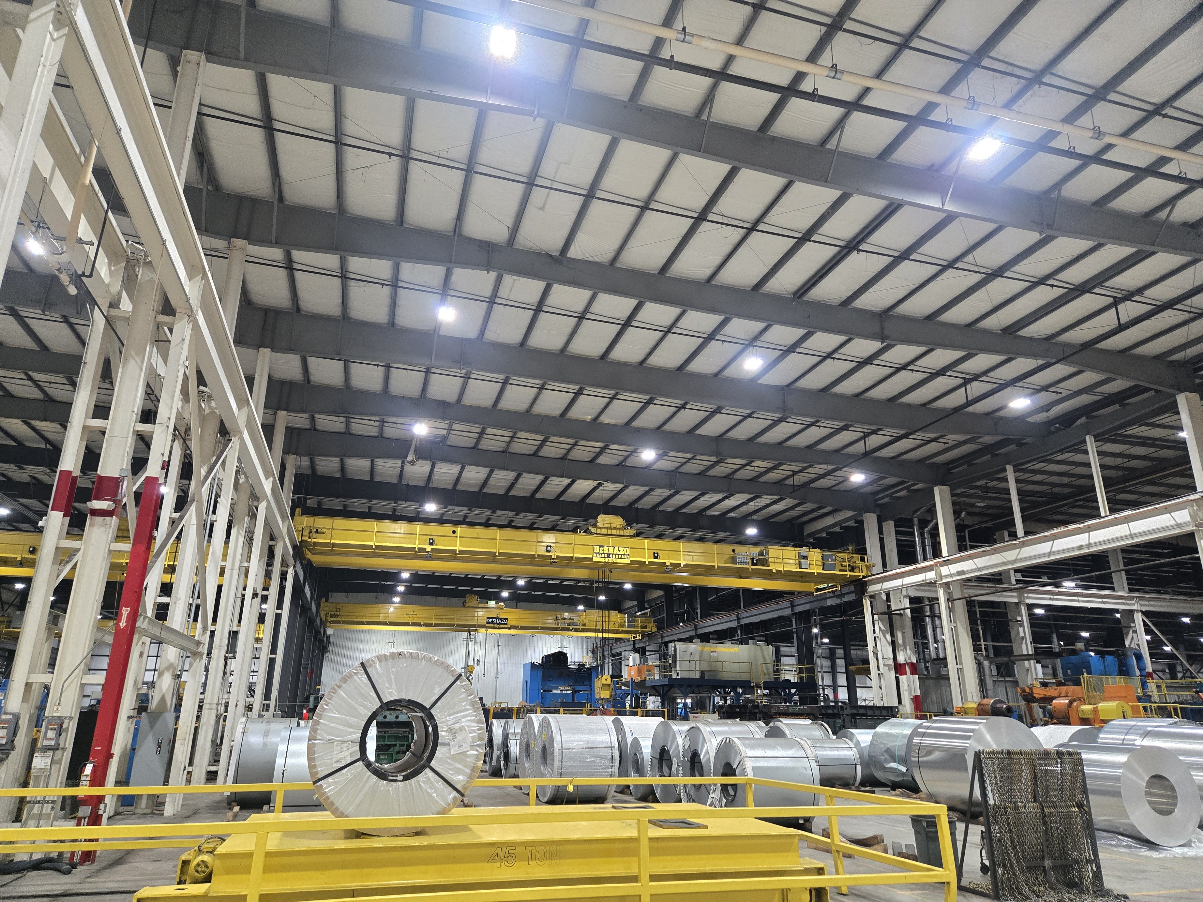 Industrial warehouse interior with overhead crane and large machinery components.