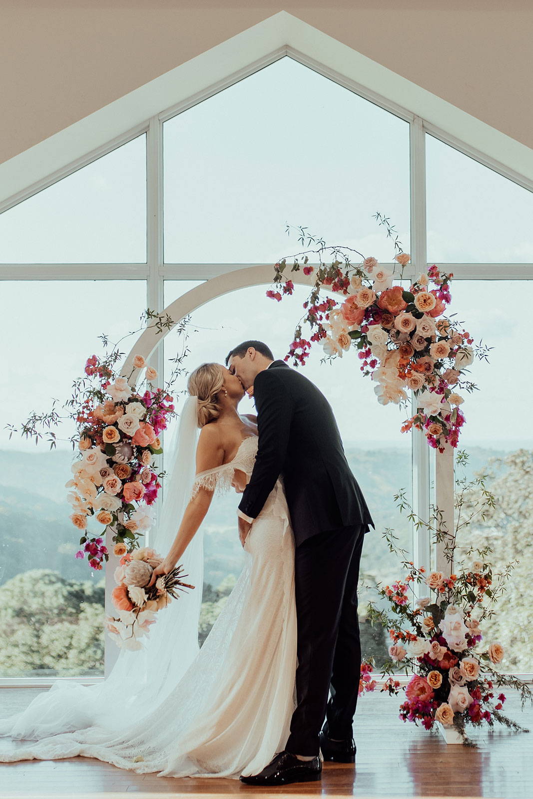 Bride and groom in front of pink floral arbor