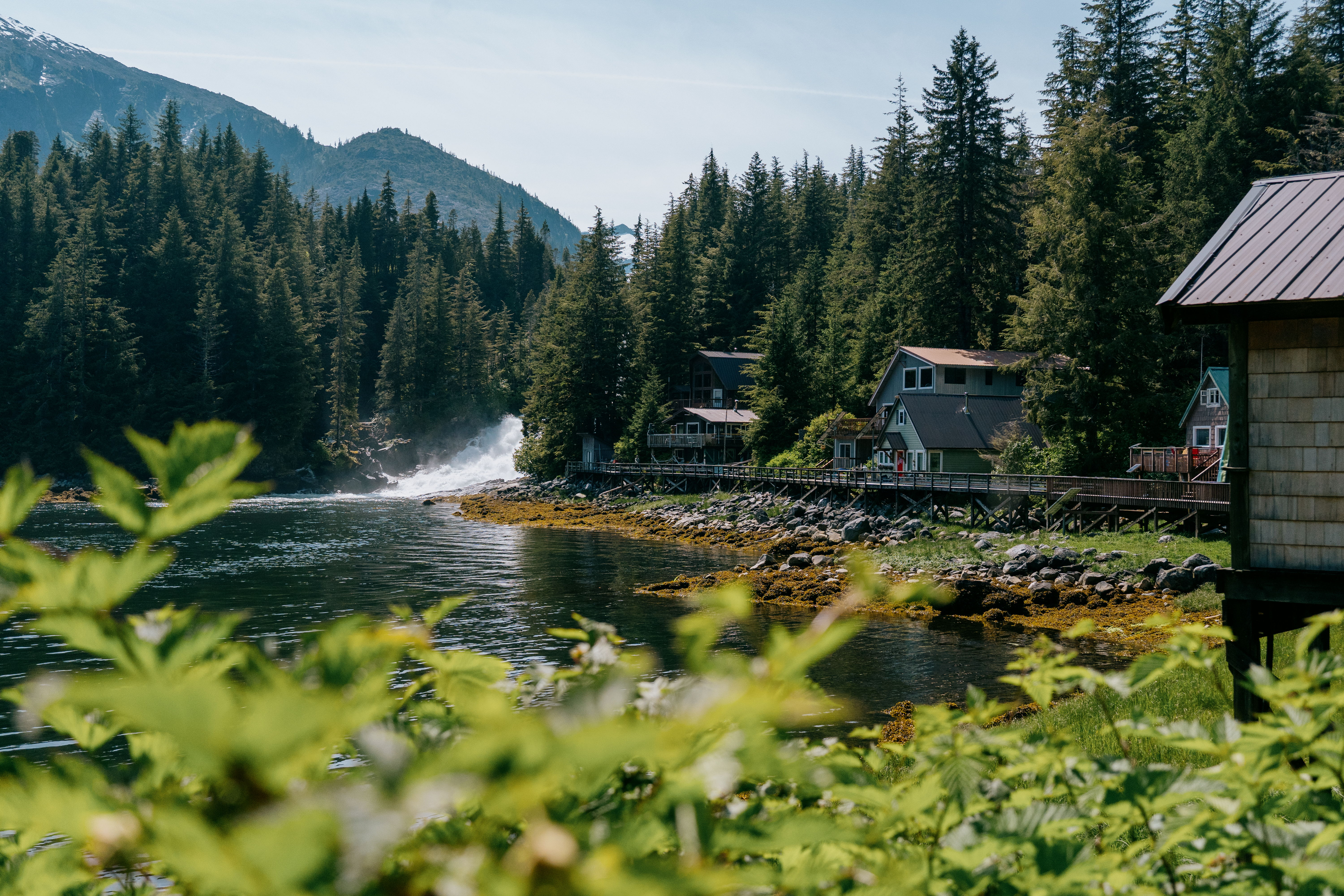 A serene lakeside view with cabins and lush greenery.