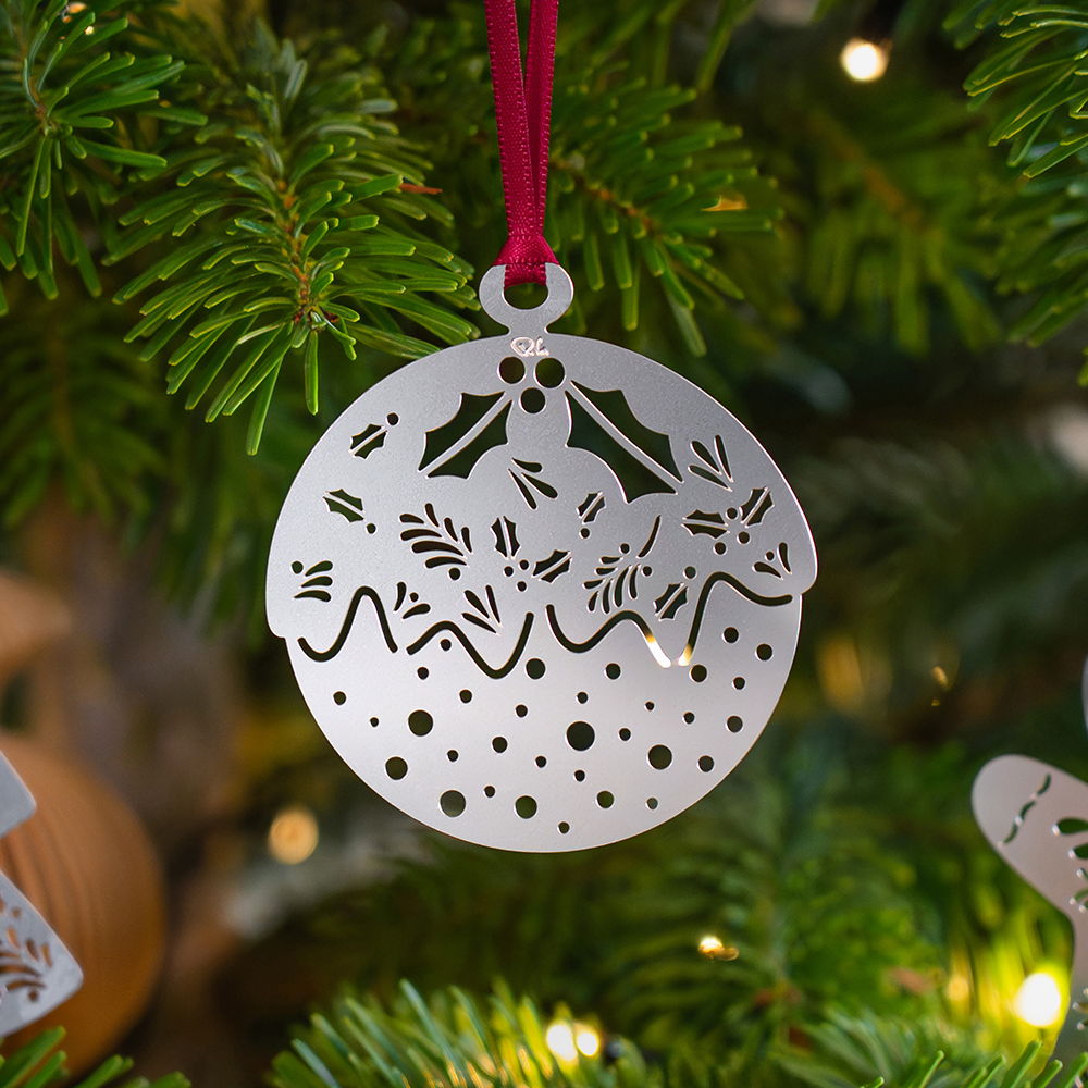Metal pudding ornament hanging on a Christmas tree.