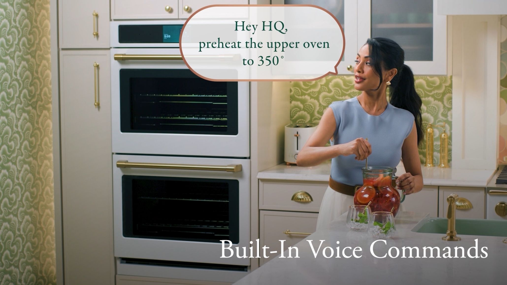 Woman in kitchen using voice command with modern appliances.