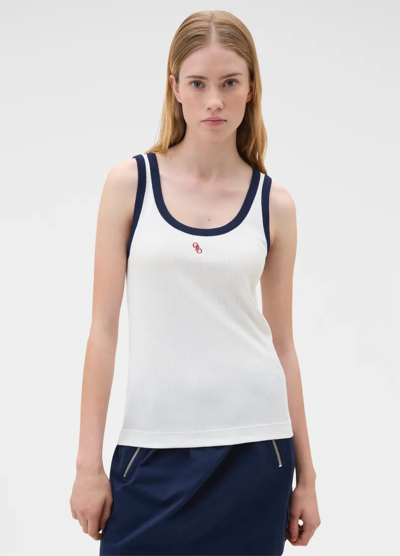 Model wearing a white tank top with navy accents and a small logo.