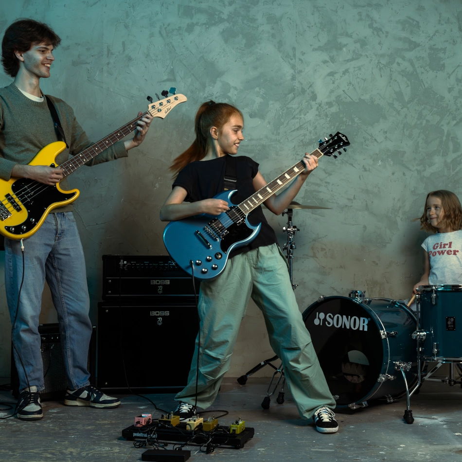 Three young musicians playing instruments in a studio setting.