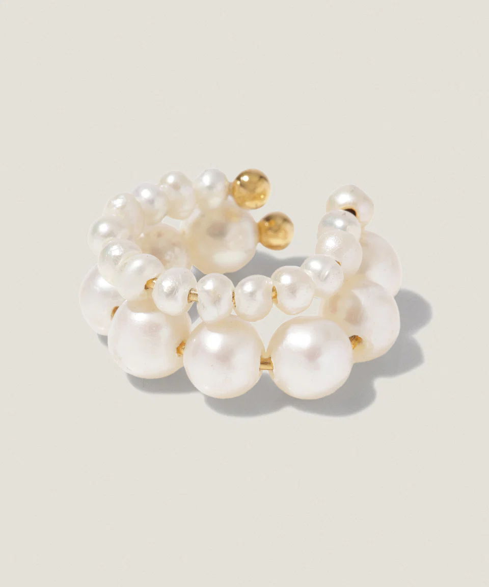 A pearl bracelet with gold accents on a light background.