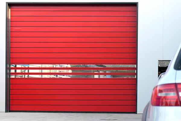 A red garage door with horizontal slats and a silver car nearby.