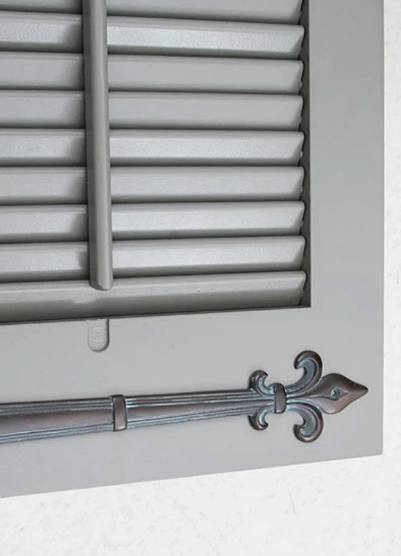 Close-up of a decorative window shutter with a metallic latch.