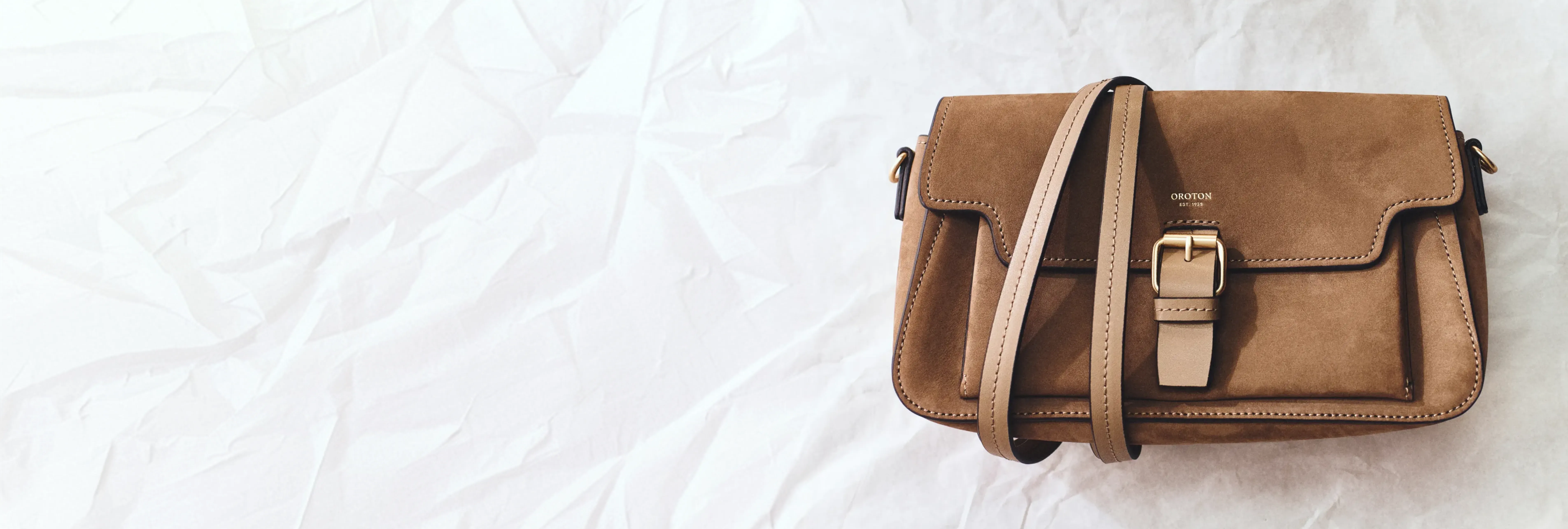 A brown leather handbag on a white surface.