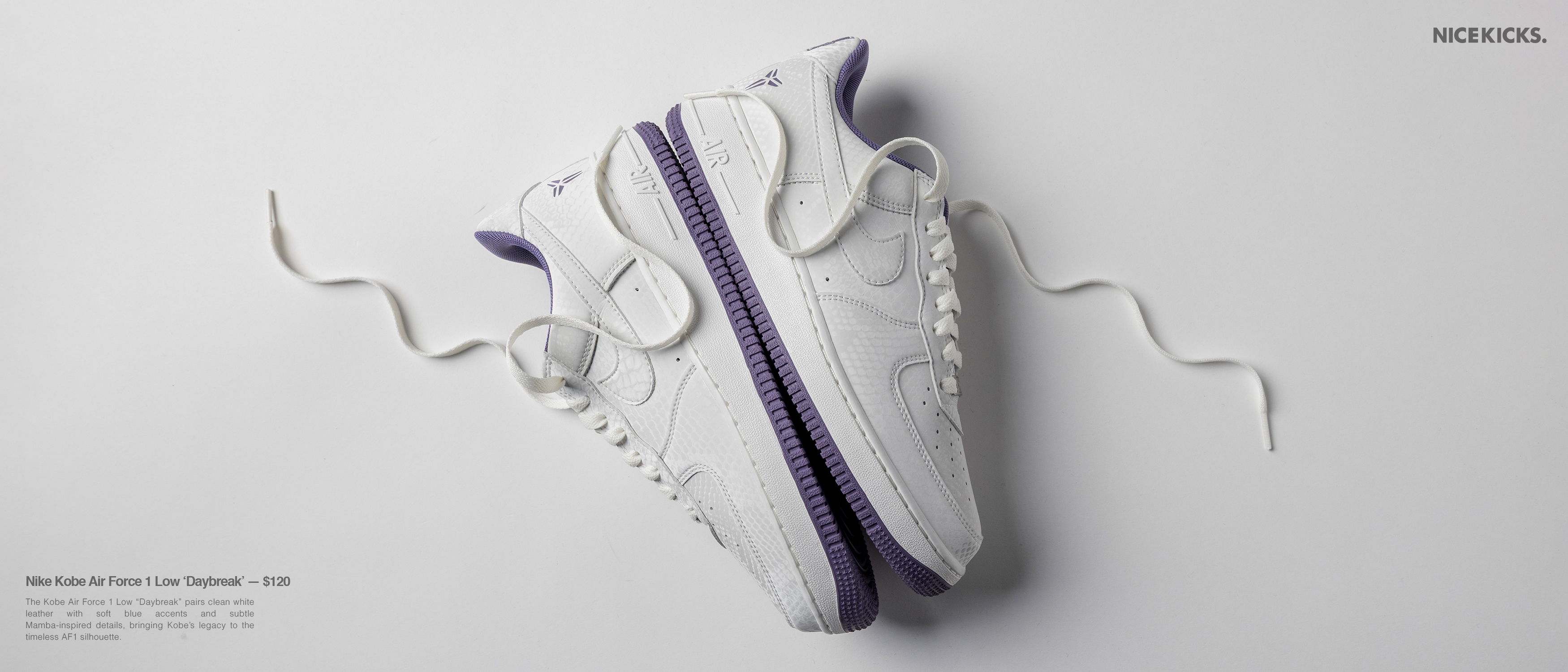A pair of white sneakers with purple accents on a light background.