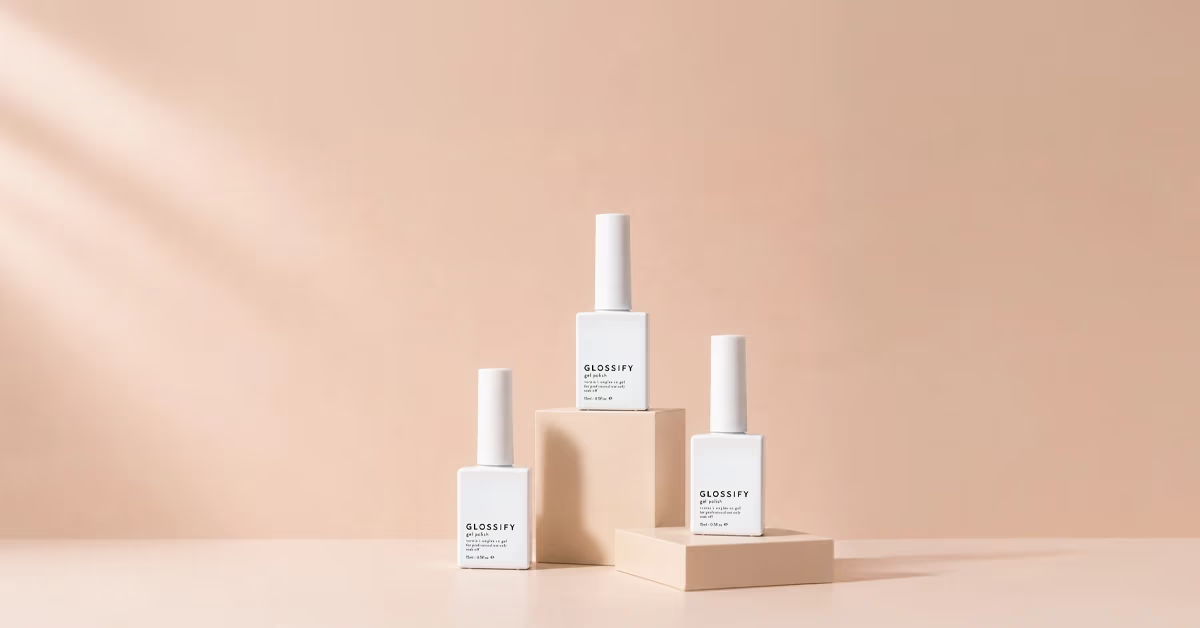 Three skincare bottles displayed on wooden blocks against a soft pink background.