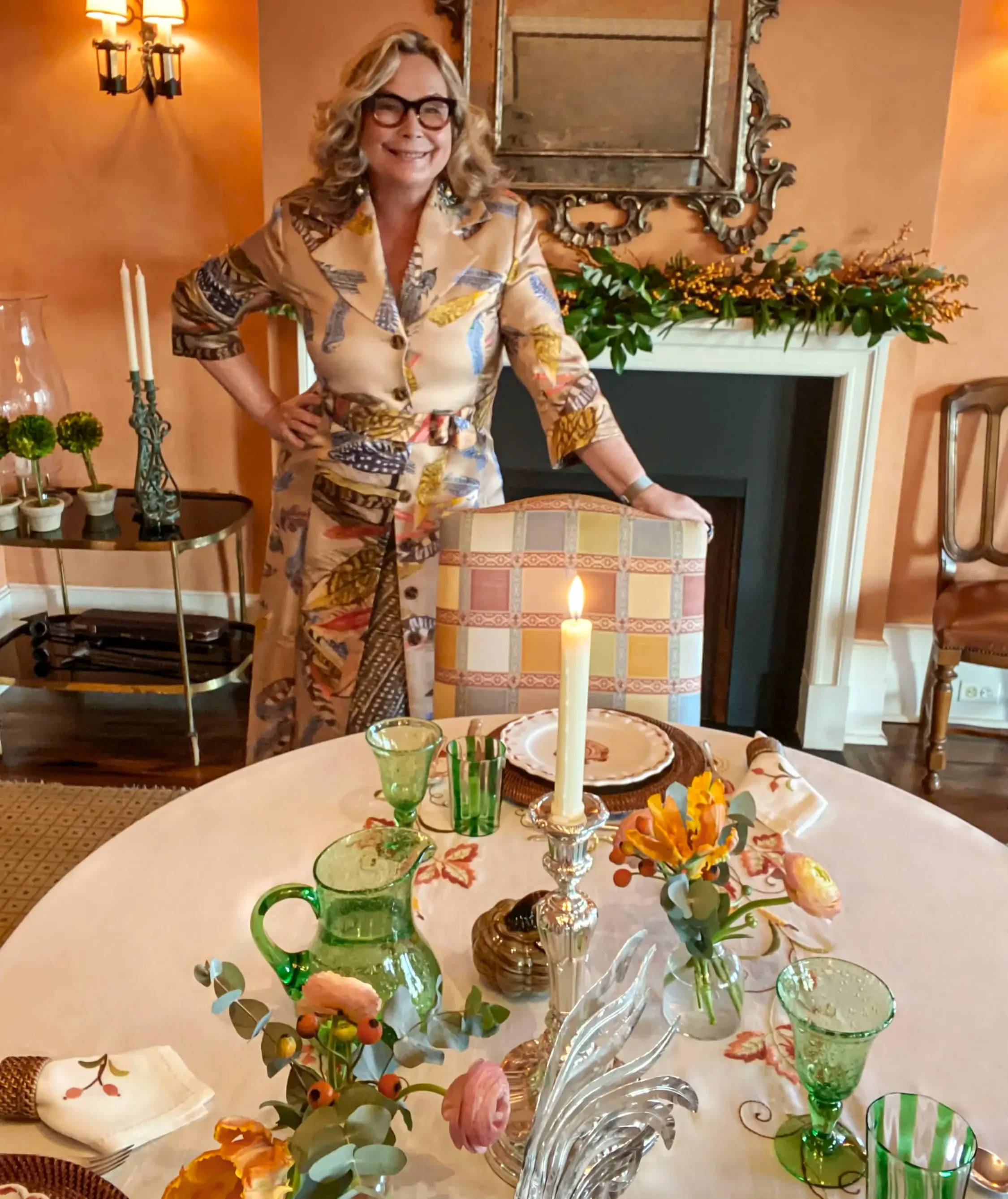 Ala Isham at her Thanksgiving table wearing feather pritned silk jacket by Ala von Auersperg