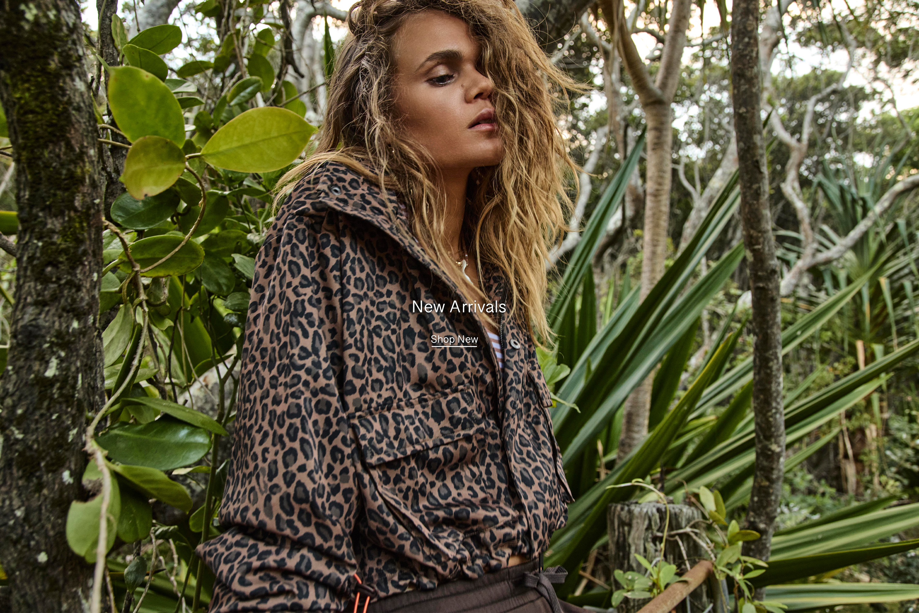Person in a leopard-print jacket surrounded by lush greenery.