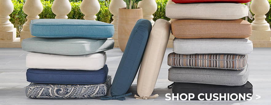 A stack of cushions and colorful outdoor rugs for sale.