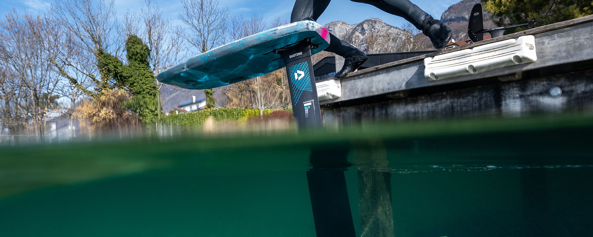 Vue sous l'eau d'une planche de pumping près d'un quai, dans une eau limpide.