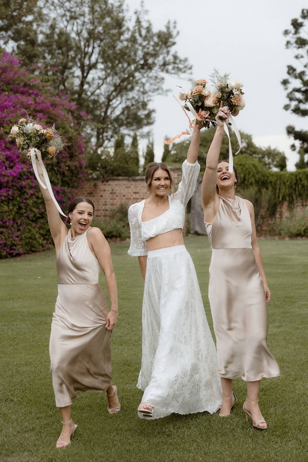 Bride and her bridesmaids holding their flower bouquets in the air